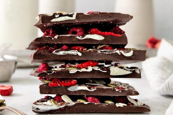 A stack of chocolate bars with raspberries and pistachios, perfect for Christmas desserts.