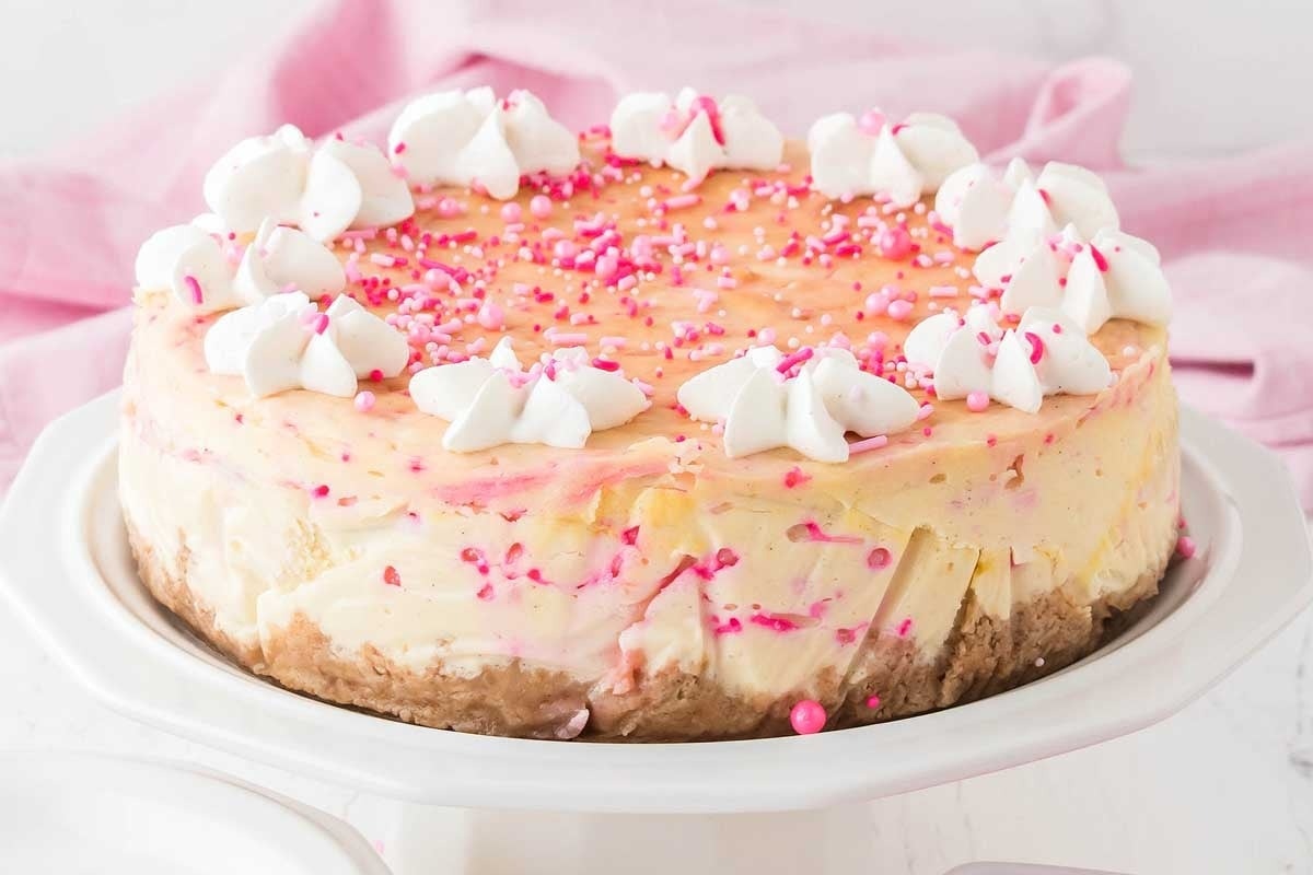 A pink and white cheesecake on a white plate.