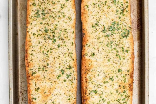 Two slices of garlic bread on a baking sheet.