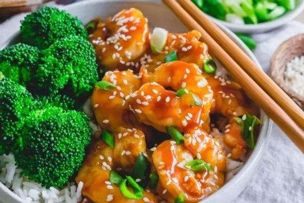 An Asian-inspired bowl of chicken and broccoli, enjoyed with chopsticks.