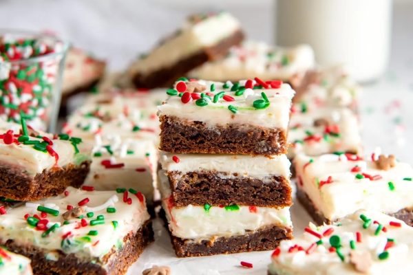 A stack of brownie bars with frosting and sprinkles.