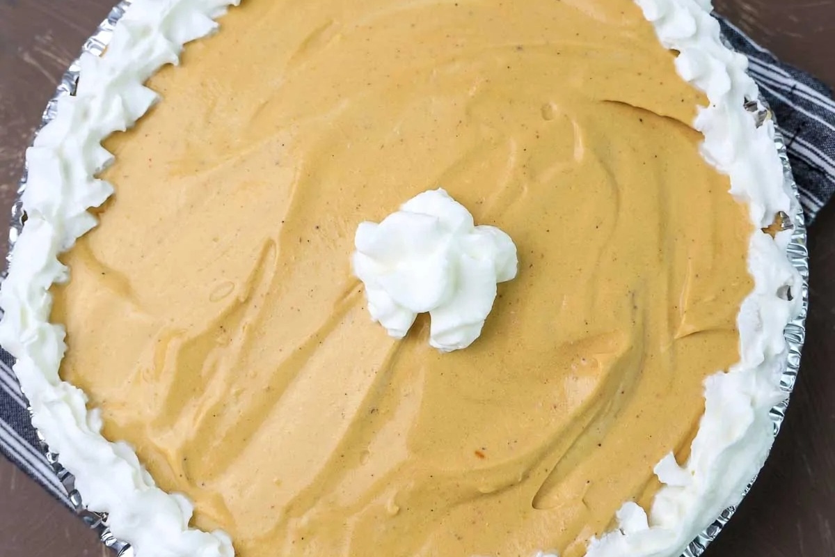 A pumpkin pie with whipped cream on top, flavored with gingerbread.