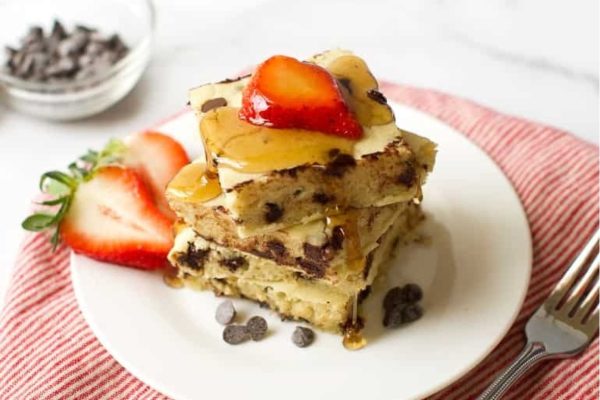 A stack of chocolate chip pancakes with strawberries on a plate, perfect for parents and kid-friendly breakfast recipes.