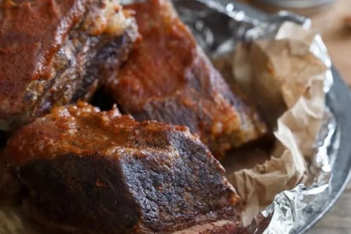 Bbq ribs recipes in foil on a wooden table.