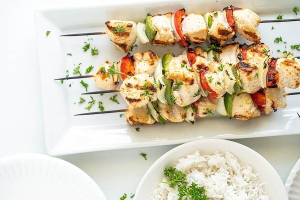 Chicken skewers on a white plate with rice.