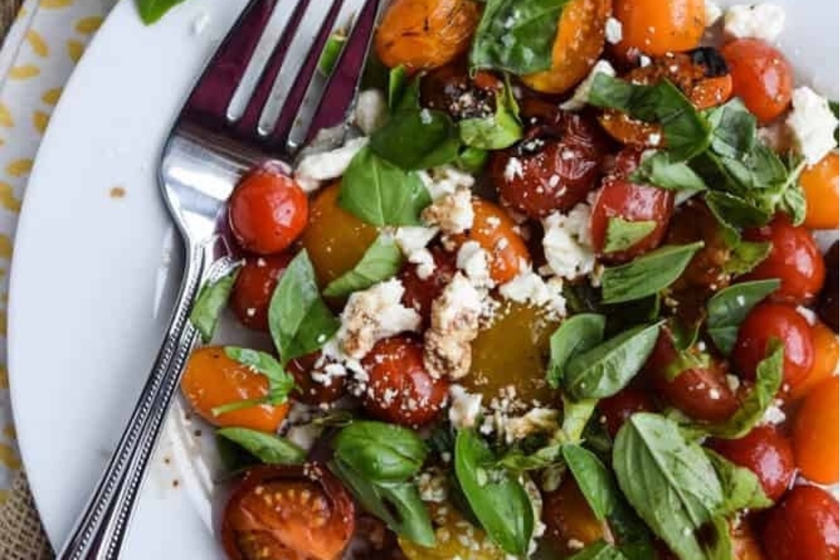 An Italian salad recipe with tomatoes, feta, and basil on a plate.