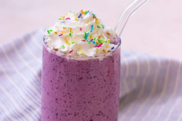 A blueberry smoothie with whipped cream and sprinkles, perfect for milkshake enthusiasts.