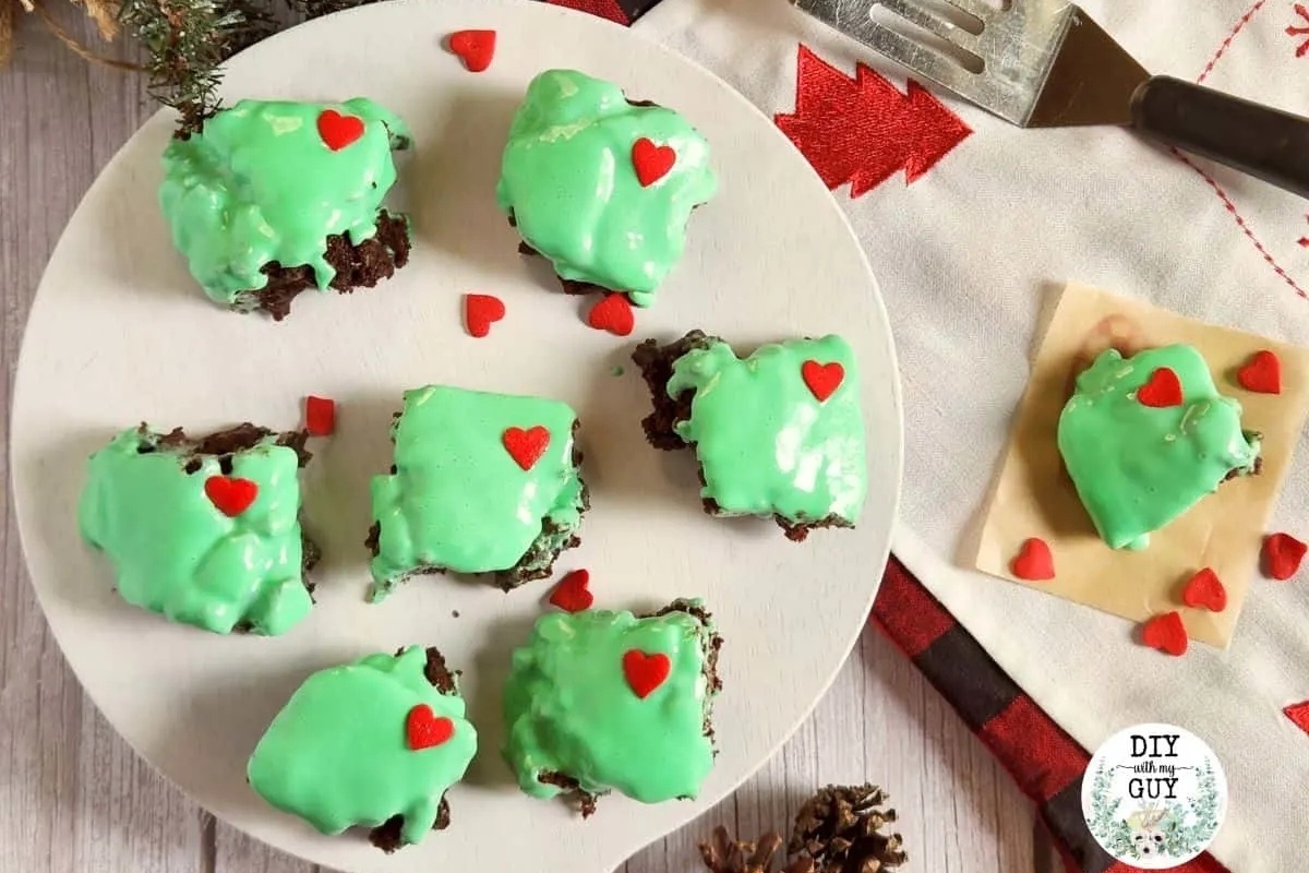 A plate of green frosted brownies with hearts on top, perfect for a Grinch-themed dessert.