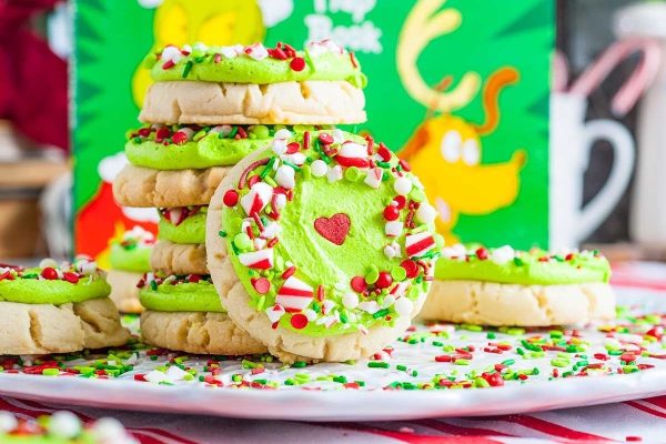 A stack of traditional Christmas cookies with green frosting and sprinkles.