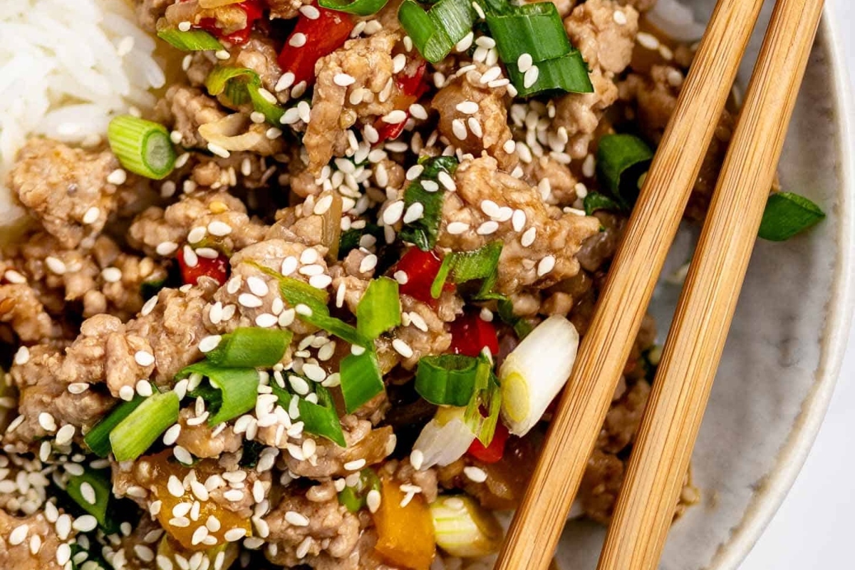 A delicious bowl of Asian meat and rice, made with ground turkey, served with chopsticks.