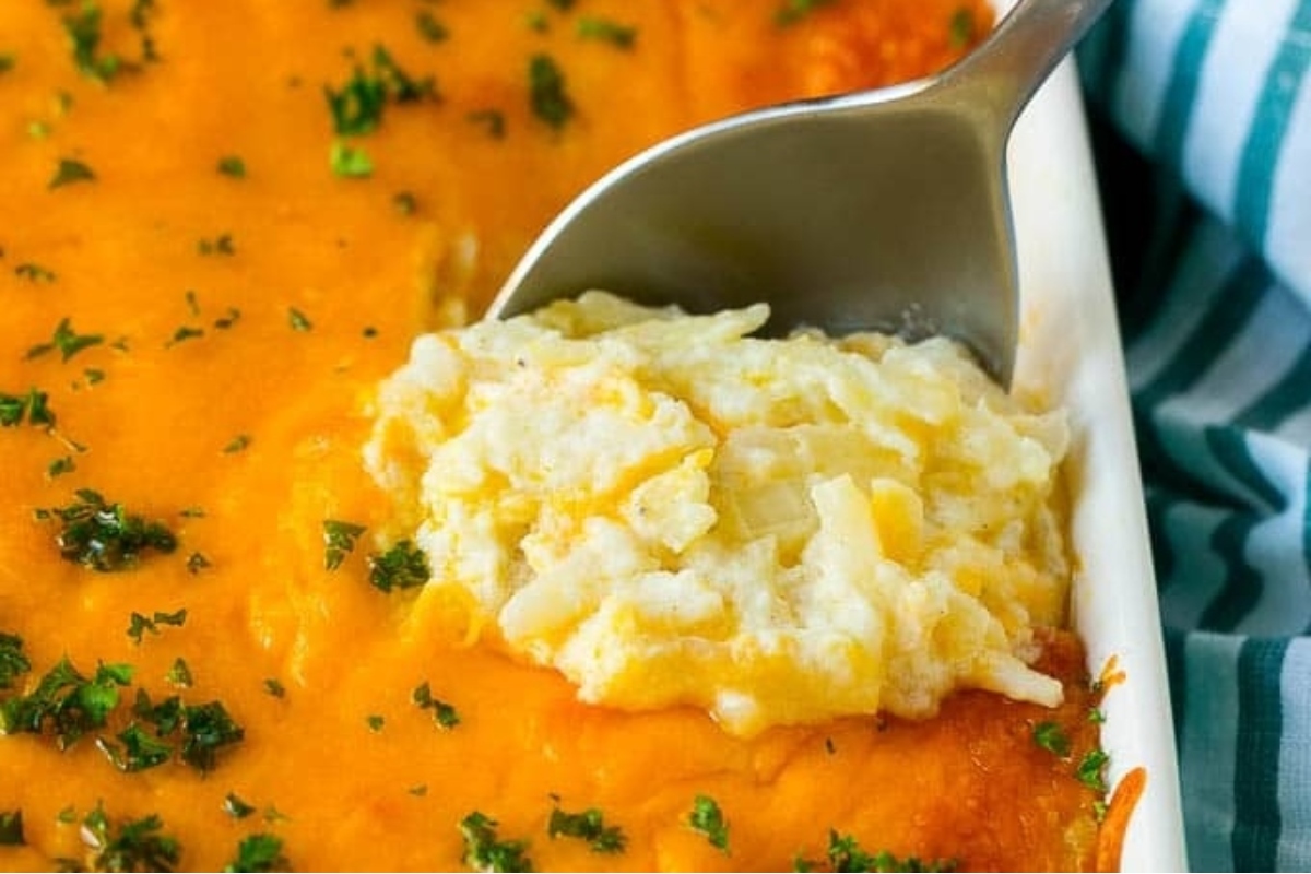 A spoonful of country style mashed potatoes in a Thanksgiving casserole dish.