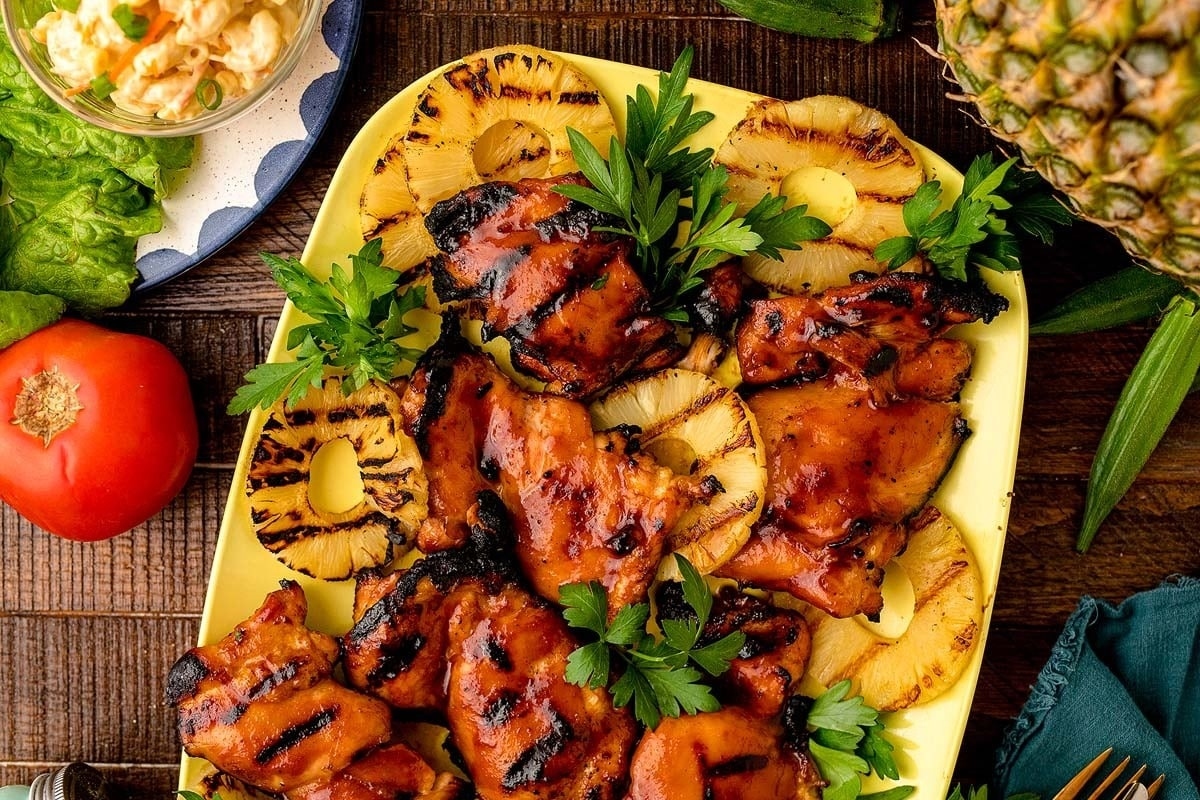 Grilled hawaiian chicken on a plate with pineapples and tomatoes.