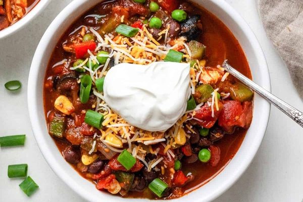 Chili in a bowl with sour cream and peas.