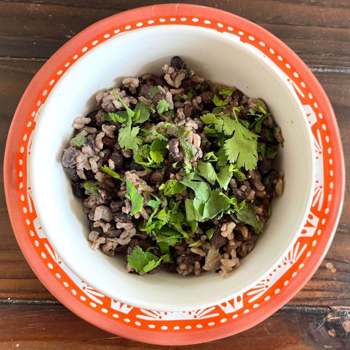 A bowl of black beans and rice on a wooden table.