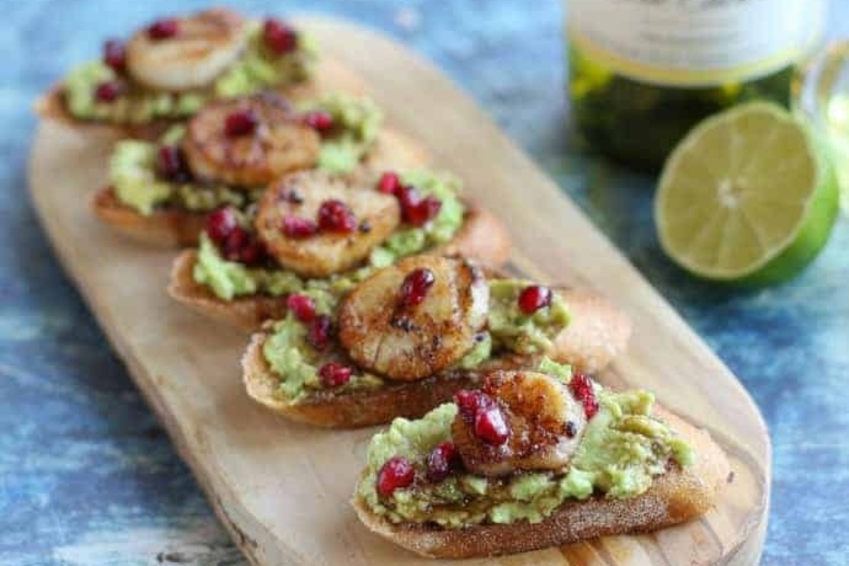 Christmas party appetizers featuring toasted bread with guacamole and pomegranate.