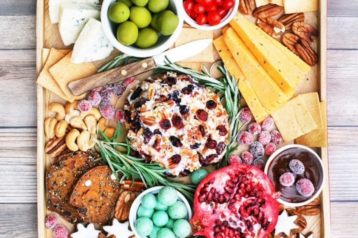A festive tray of cheese, nuts, and fruit arranged beautifully on a wooden table for a delightful Christmas gathering.