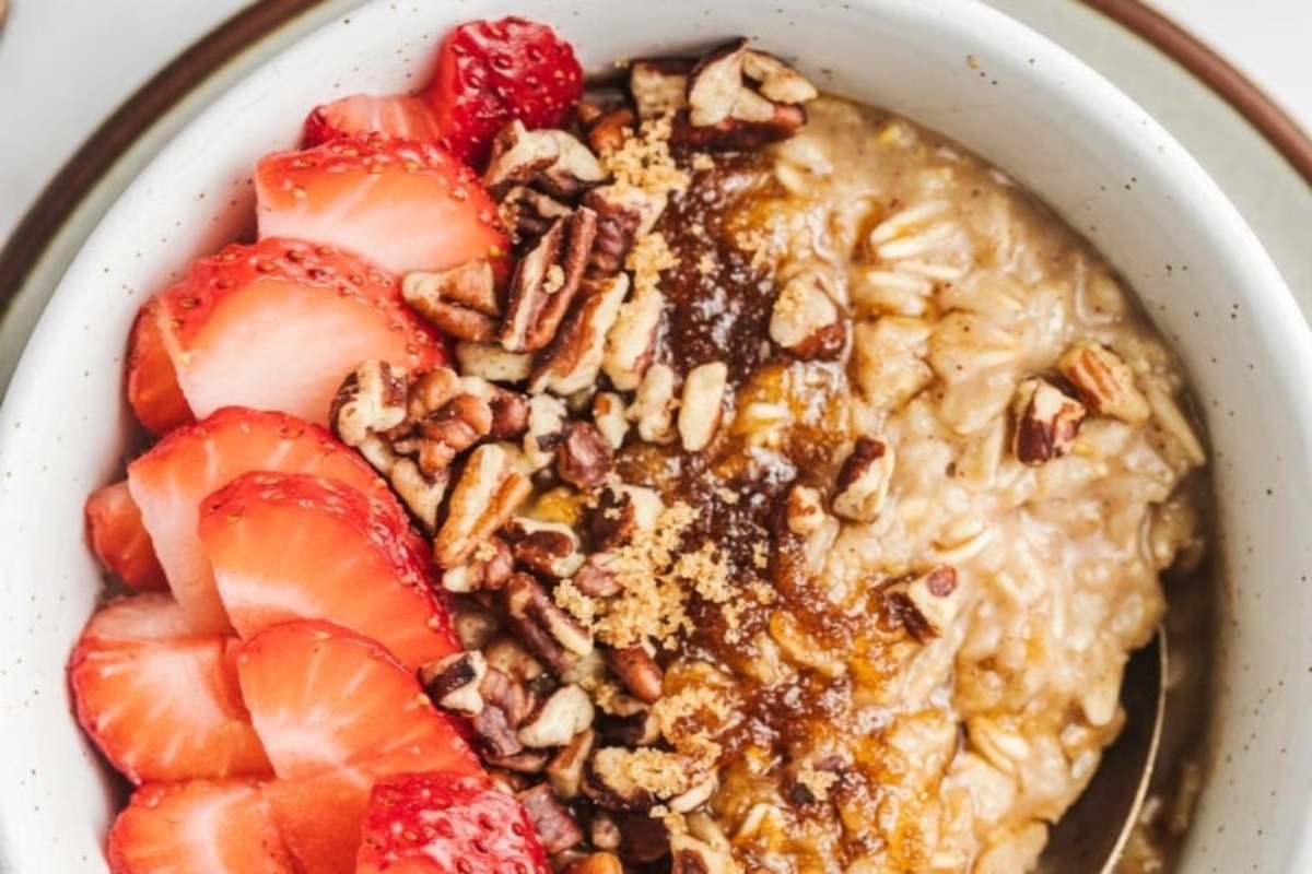 A bowl of oatmeal with strawberries, pecans, and cinnamon.