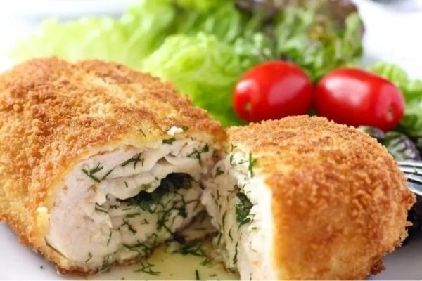 Chicken stuffed with dill and tomatoes on a plate.