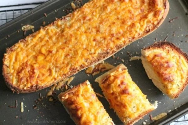 Two slices of cheesy bread on a baking sheet.