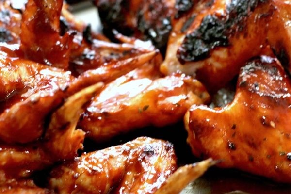 Game day enthusiasts will find themselves salivating over the delectable display of BBQ chicken wings resting on a plate.