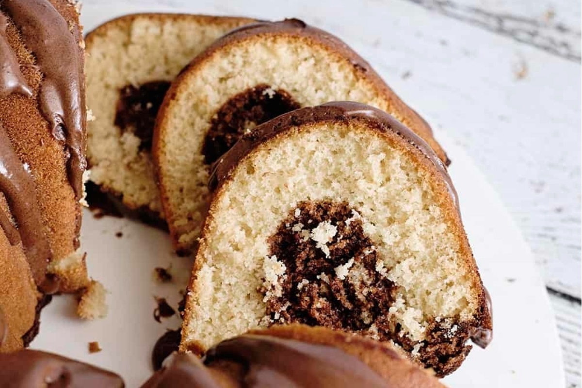 A Bundt cake with rich chocolate icing elegantly displayed on a plate.