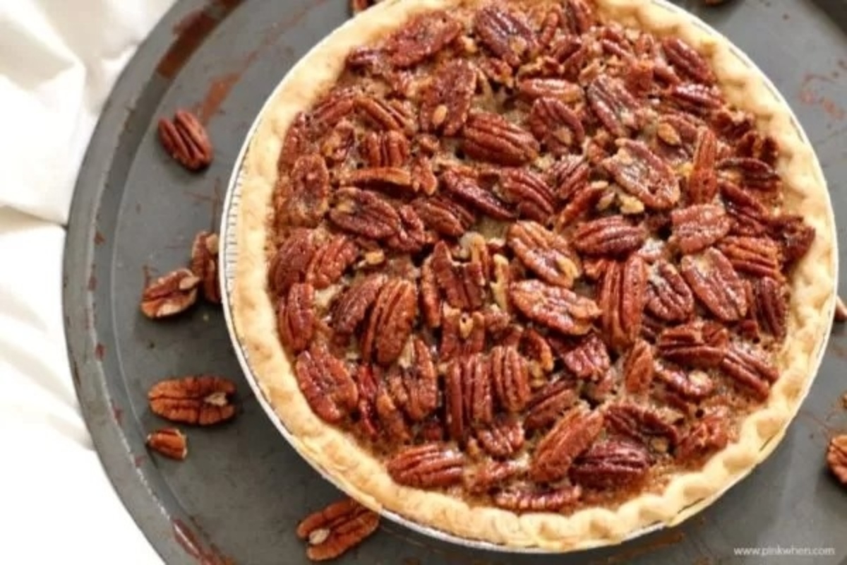 Pecan pie on a plate with pecans.