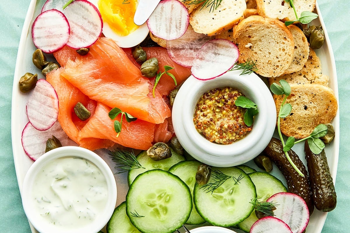 A festive plate with smoked salmon, cucumbers, radishes and crackers fit for a Christmas party appetizer.