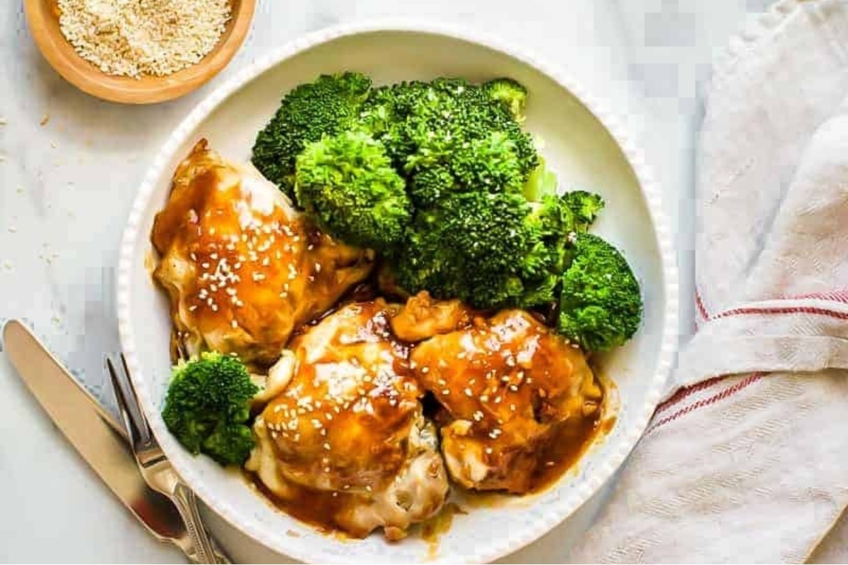 A plate of chicken and broccoli with sesame sauce.