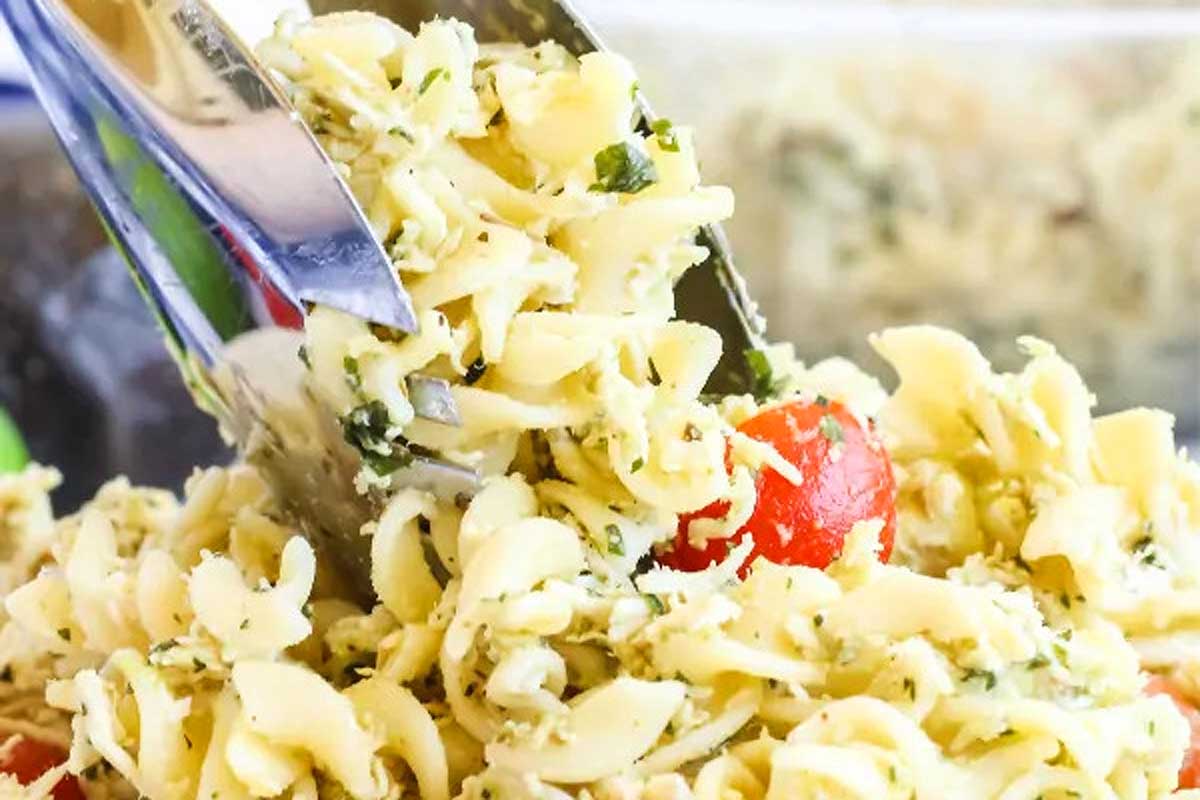 A fork is being used to pick up a bowl of pasta salad.