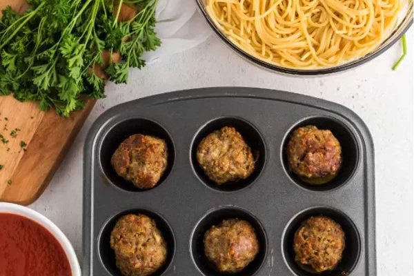 Meatballs and pasta in a muffin tin.