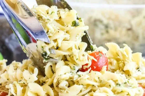 A fork is being used to scoop pasta salad out of a bowl.