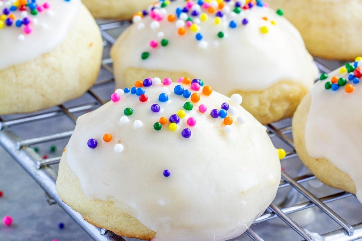White icing cookies with sprinkles on a cooling rack, perfect as a delightful Italian dessert.