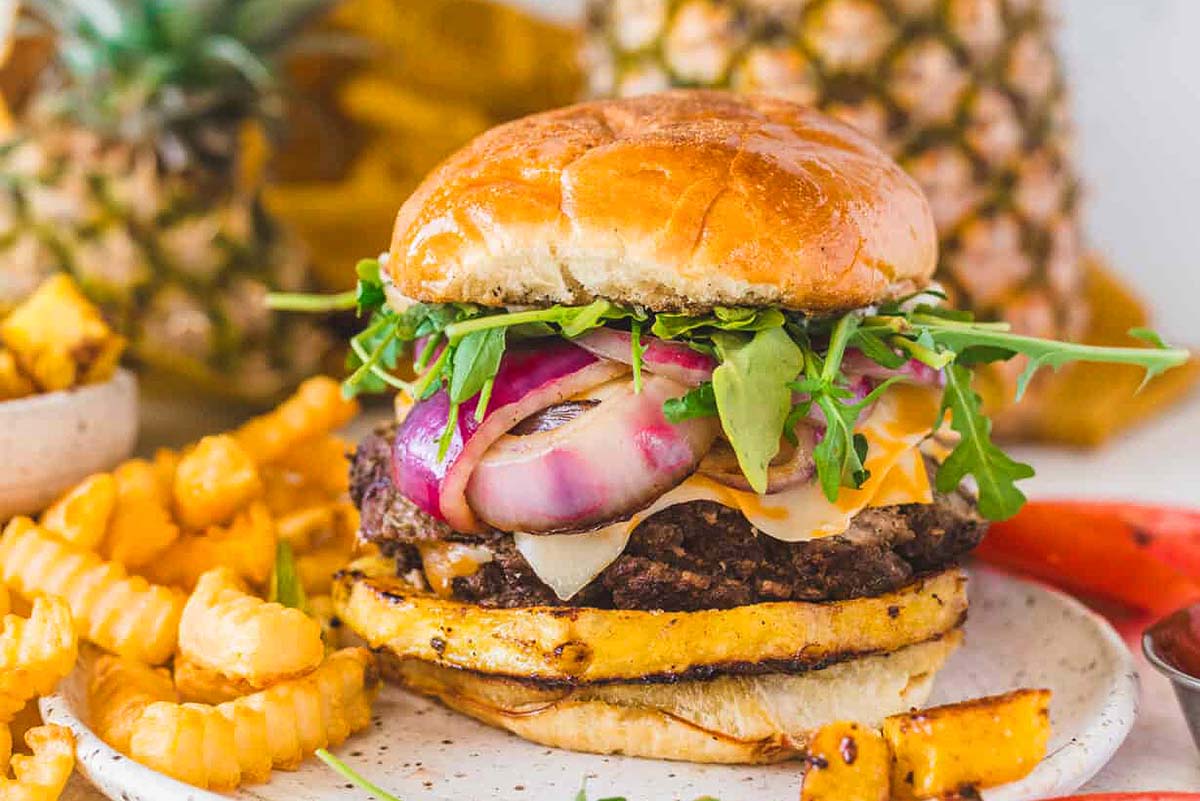 A pineapple burger on a plate with fries.
