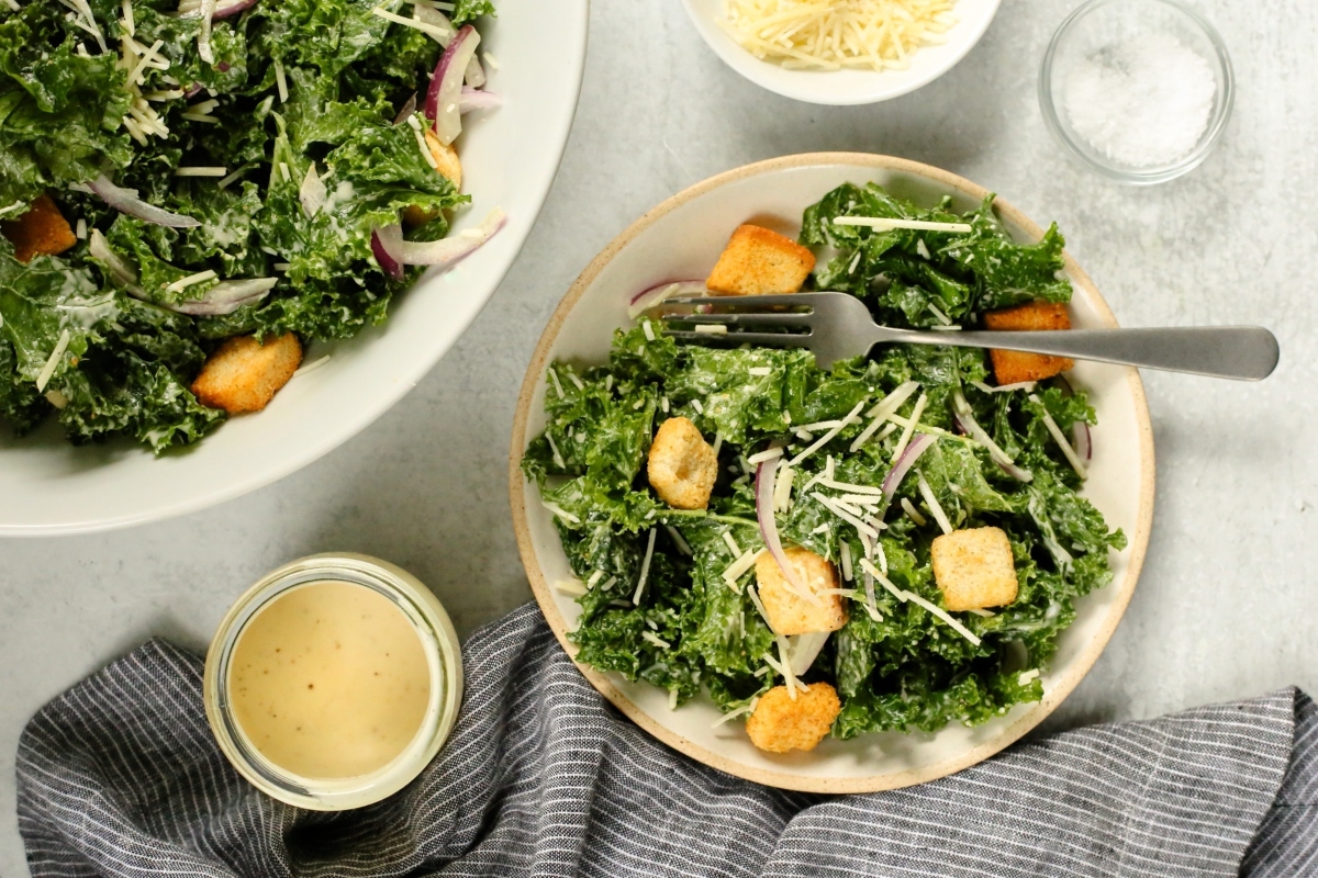 A bowl of kale salad with croutons and dressing, perfect as a healthy side dish.