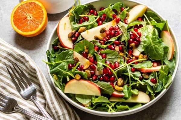 A bowl of kale salad with pomegranate and pomegranate.