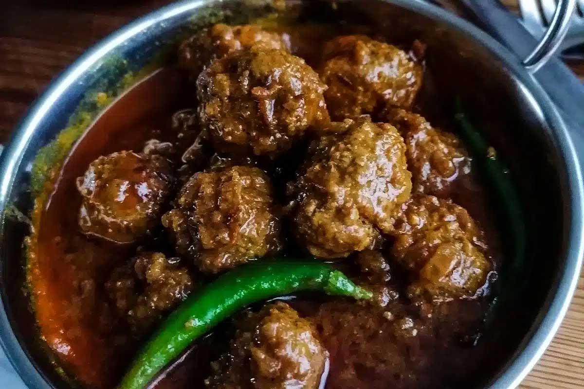 A bowl of meatballs in a sauce on a wooden table.