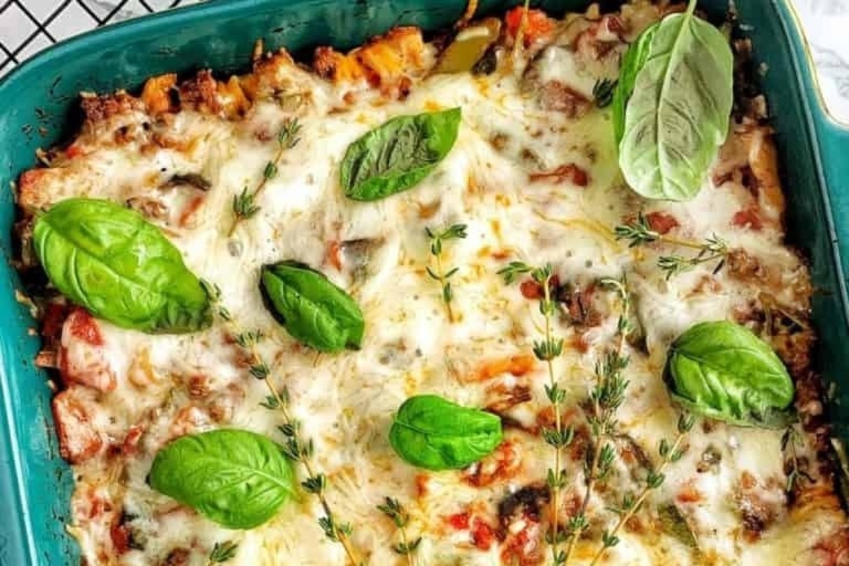 A dish of lasagna with cheese and basil leaves.