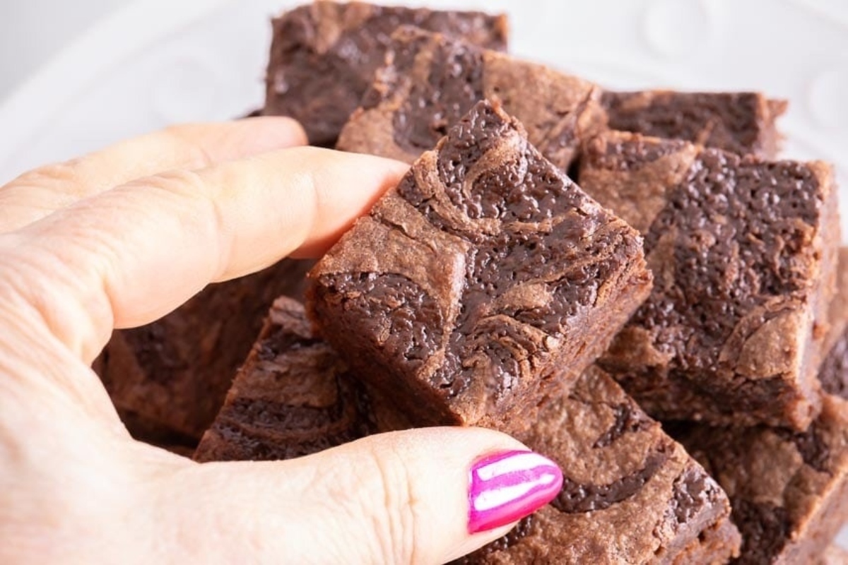 A person holding up a plate of delicious Nutella brownies.