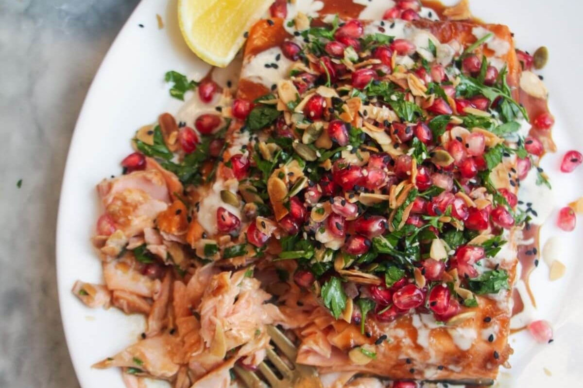A plate with salmon and pomegranate on it, perfect for a delicious pomegranate-infused recipe.