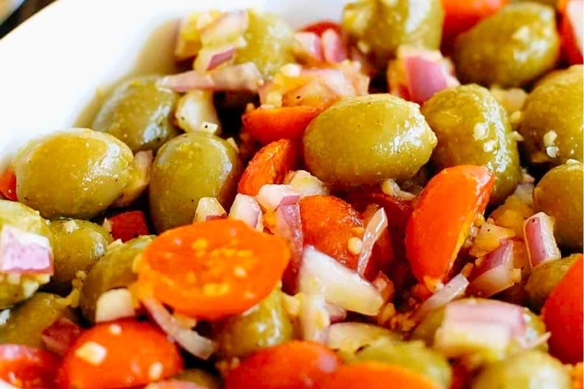 Italian Salad: Olives, tomatoes and onions in a white bowl.