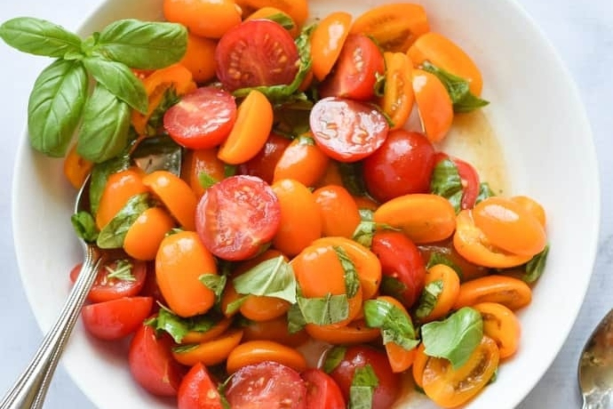 Italian salad with tomatoes and basil in a white bowl.