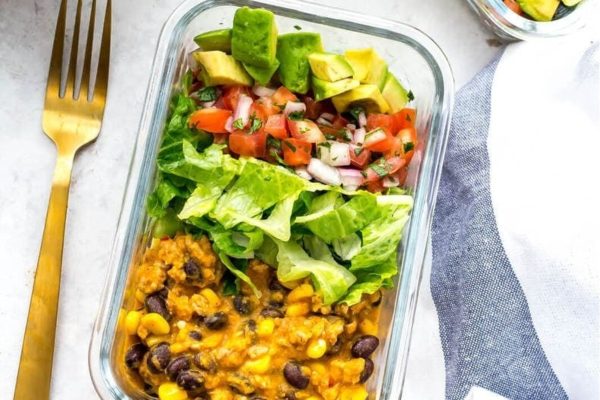 A nutritious meal prep option for lunches, featuring a delectable blend of avocado, black beans, and rice conveniently packed in a glass container.