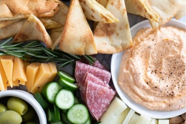 A platter of dips, olives, cucumbers and crackers.