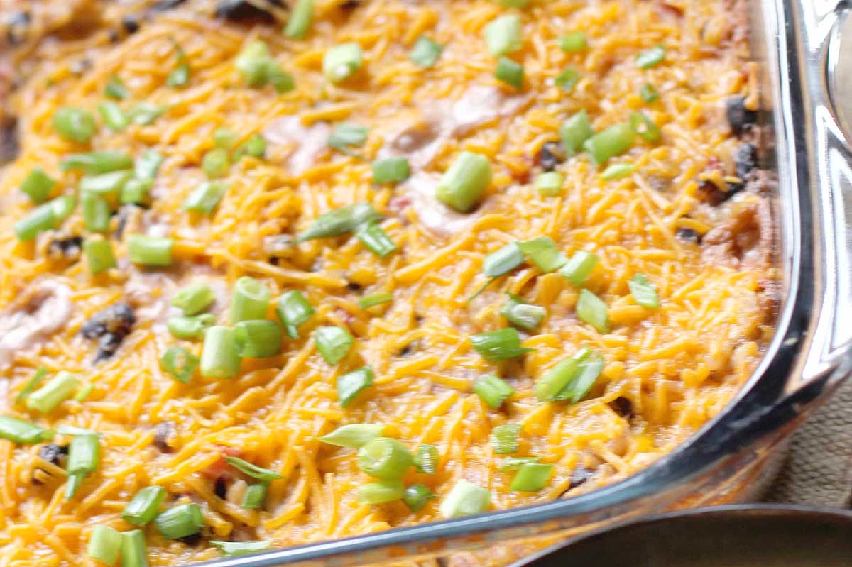 A casserole dish with cheese and green onions.