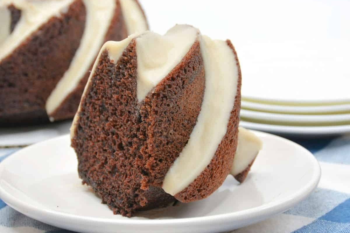 A decadent Bundt cake with white icing on a plate.