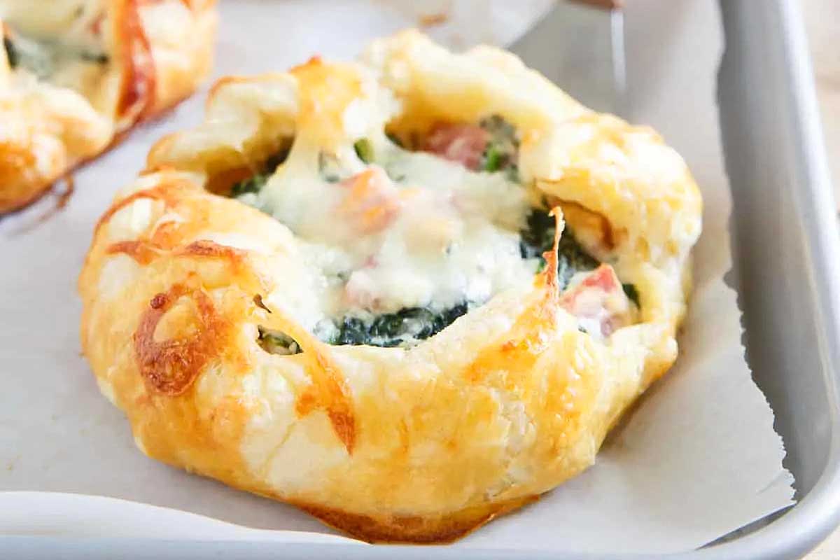 Brunch recipes: Ham and spinach puff pastries on a baking sheet.