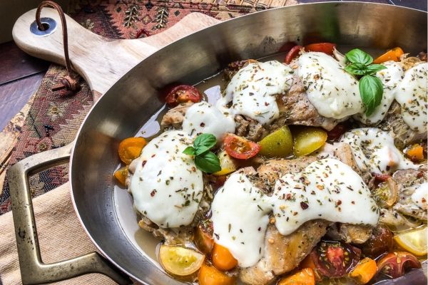 Chicken with tomatoes and mozzarella in a skillet.