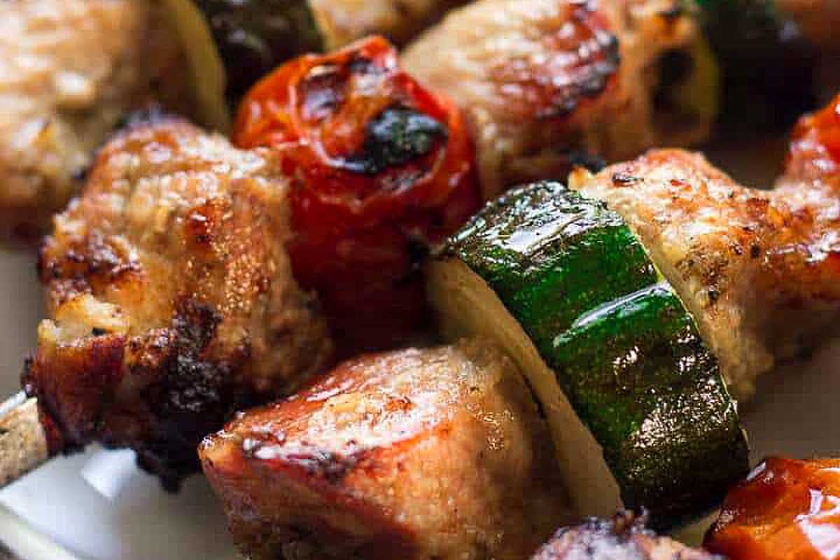Meat skewers with zucchini and tomatoes on a plate.