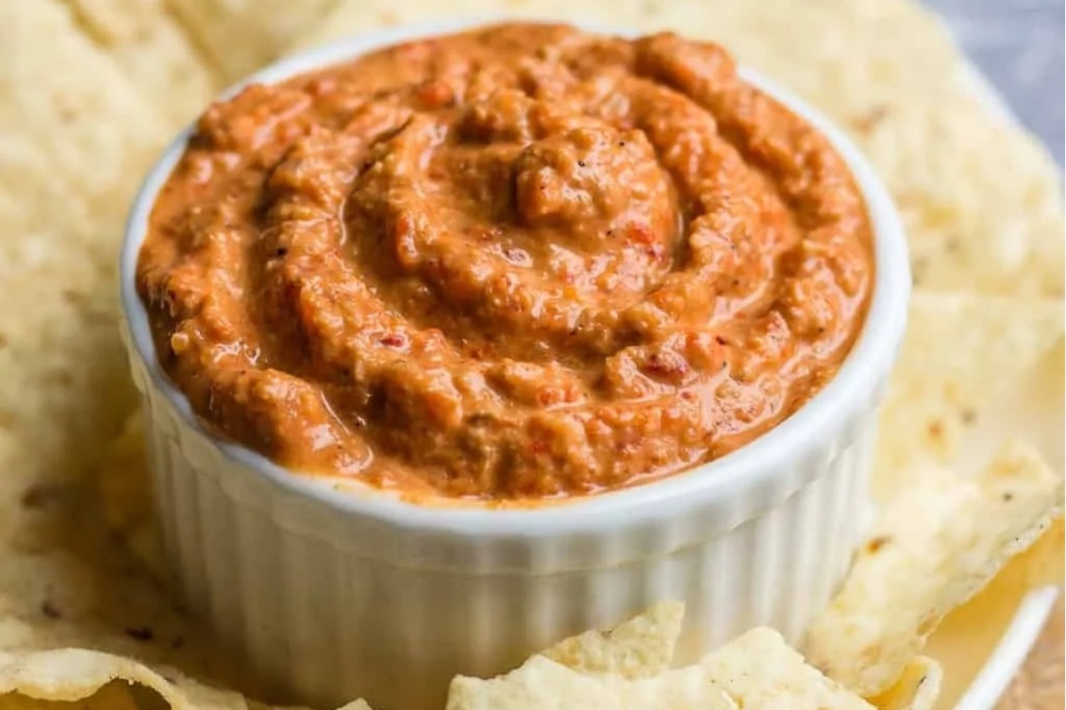 A festive bowl of Mexican dip, perfect for a Christmas party appetizer, surrounded by crispy tortilla chips.