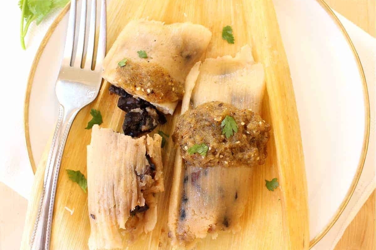 Two mushroom tamales on a plate with a fork.